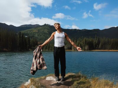 TJ posing in the cliff with lake and mountain at the back